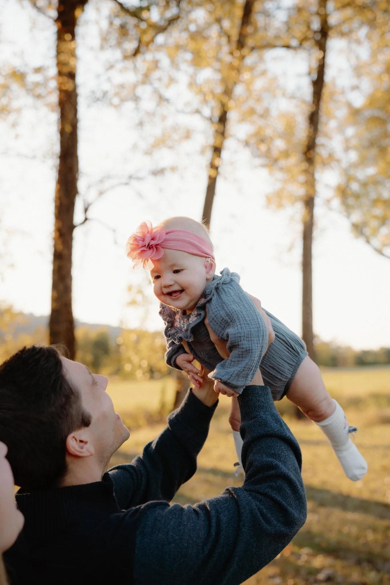 Leo lifting his daughter Lydia into the air among autumn trees